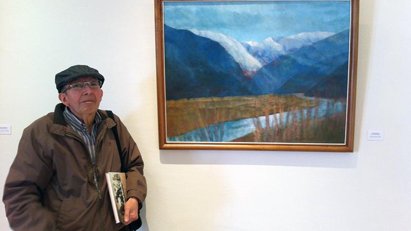 El artista Franklin Gahona junto a su obra "Valle Místico" perteneciente a la Pinacoteca de la Universidad Católica del Norte.