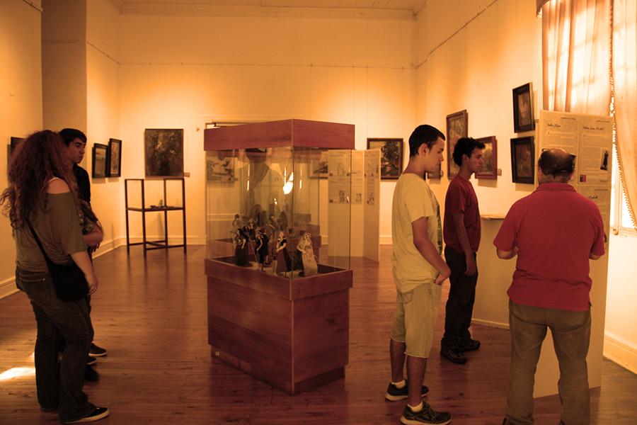Visitantes admirando la exposición de muñecas de porcelana.